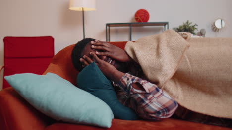 terrified scared african american young man wakes up from stress nightmare in bedroom at home sofa