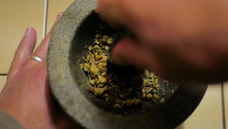 using a granite mortar and pestle to crush green peppercorns