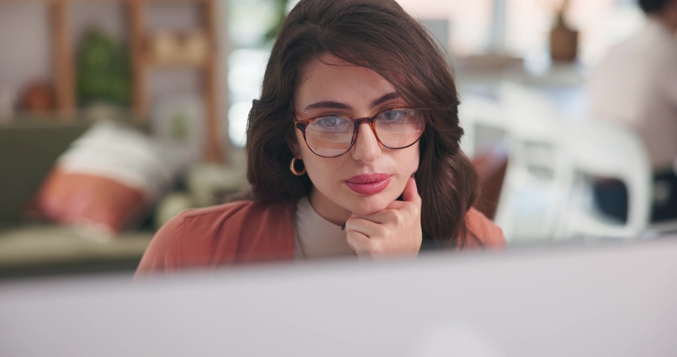 Giovane donna concentrata che lavora al computer in un ufficio moderno
