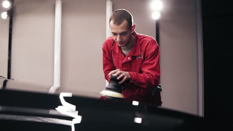 polishing black car surfacewith a professional polishing mashine using wax