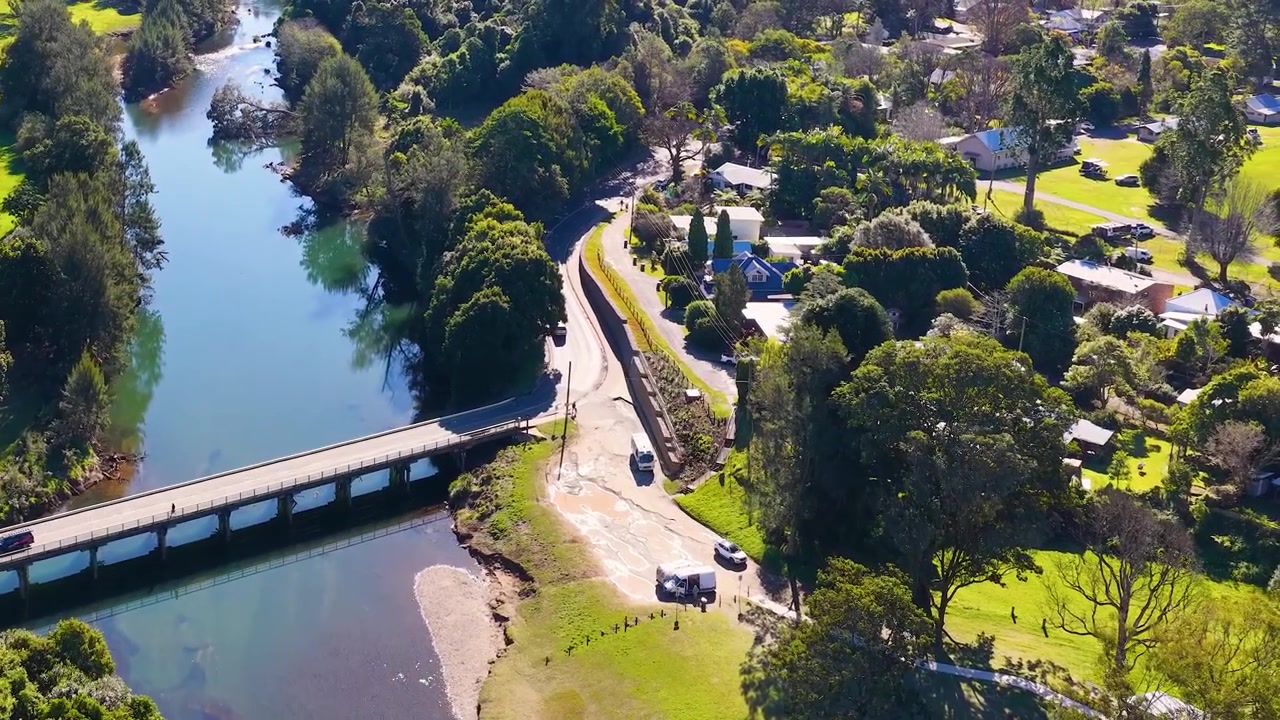 Ripresa aerea con drone di un ponte su un fiume circondato da alberi verdi lussureggianti.