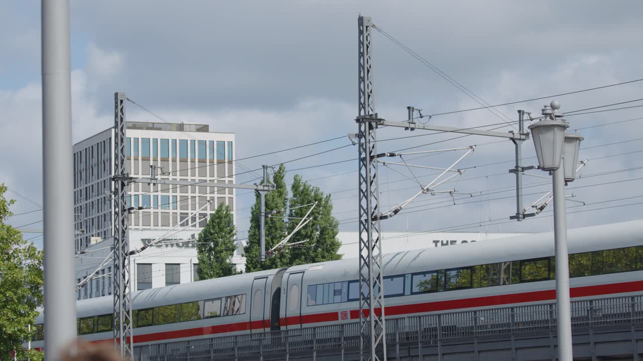 Modern high-speed passenger train crossing elevated railway in Berlin cityscape with greenery, daytime