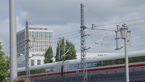 modern high-speed passenger train crossing elevated railway in berlin cityscape with greenery, daytime
