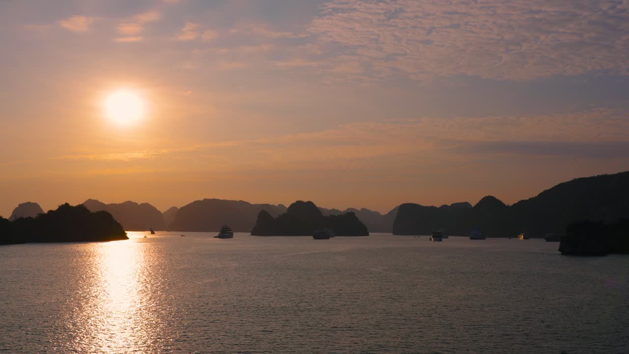 Sunset at Halong Bay, cruise ships on anchor back lit with rising sun, Vietnam