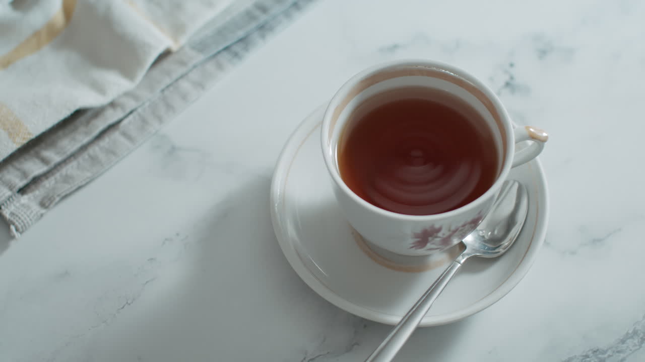 백자 컵에 담긴 차의 진동은 클로즈업 매크로 샷에서 액체 표면에 파도의 원으로 나타납니다.