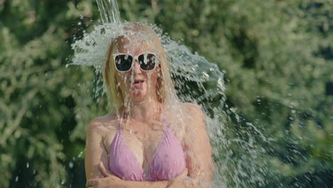 woman splashing water on her head in a garden