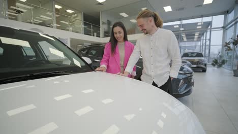 beautiful young couple at car showroom choosing a new car to buy.