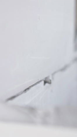 professional worker holds large grey gypsum pasteboard and puts on wall top with grey substance close view