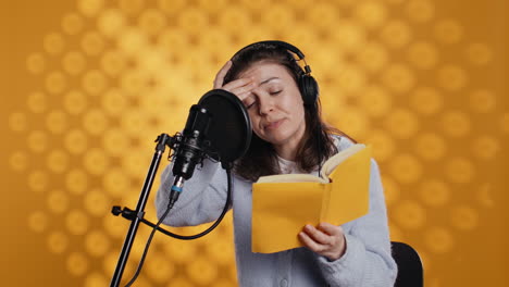 Woman-feeling-tired-while-doing-voiceover-of-book,-studio-background