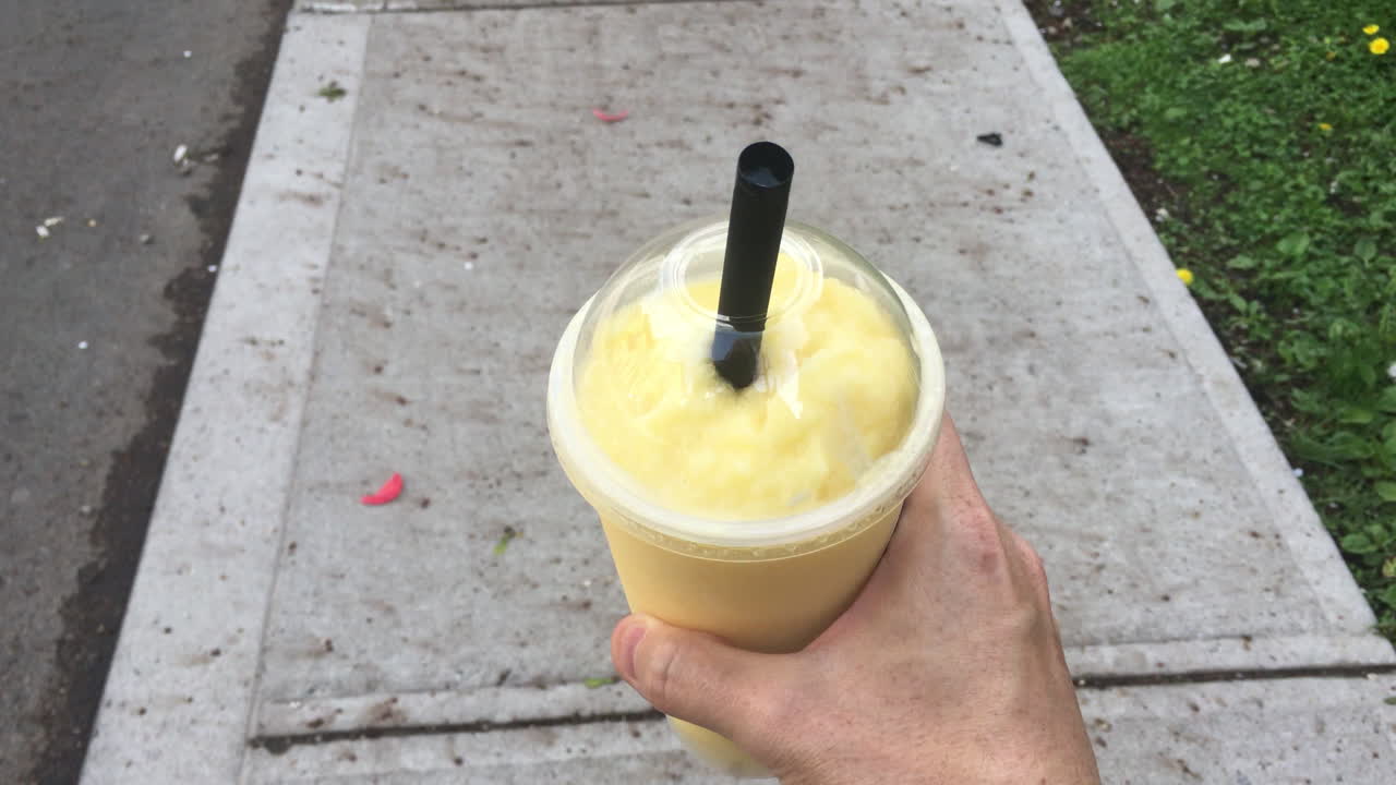 hombre caminando por un sendero sosteniendo un té de burbujas batido de mango fresco en toronto, ontario, canadá