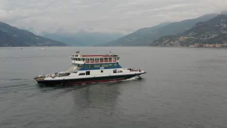 aerial of ferry driving over lake como towards a distant town in italy