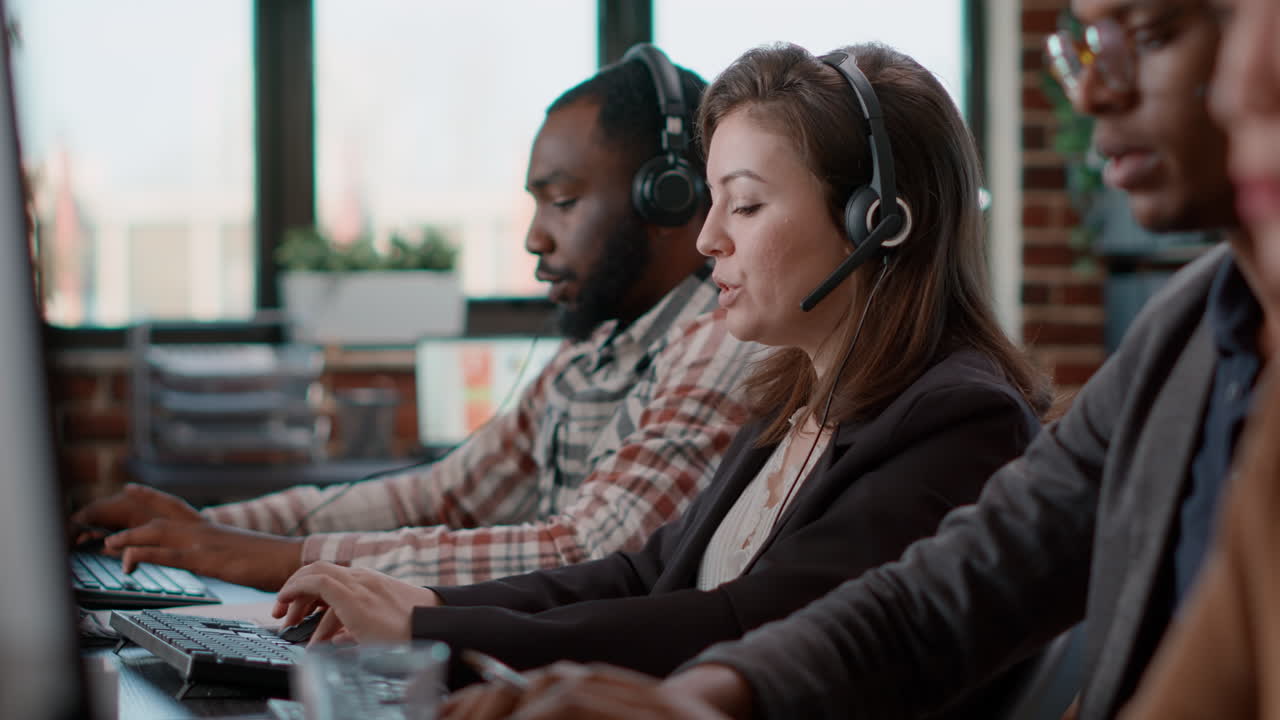Young woman using audio headset and computer at call center