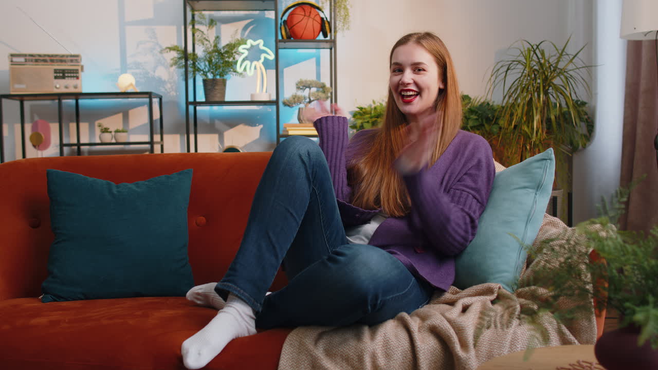 Pretty woman smiling friendly at camera waving hands gesturing hello hi greeting at home on sofa