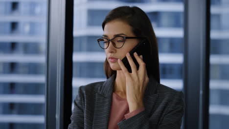 Displeased-businesswoman-talking-on-mobile-phone-with-business-partner-in-office