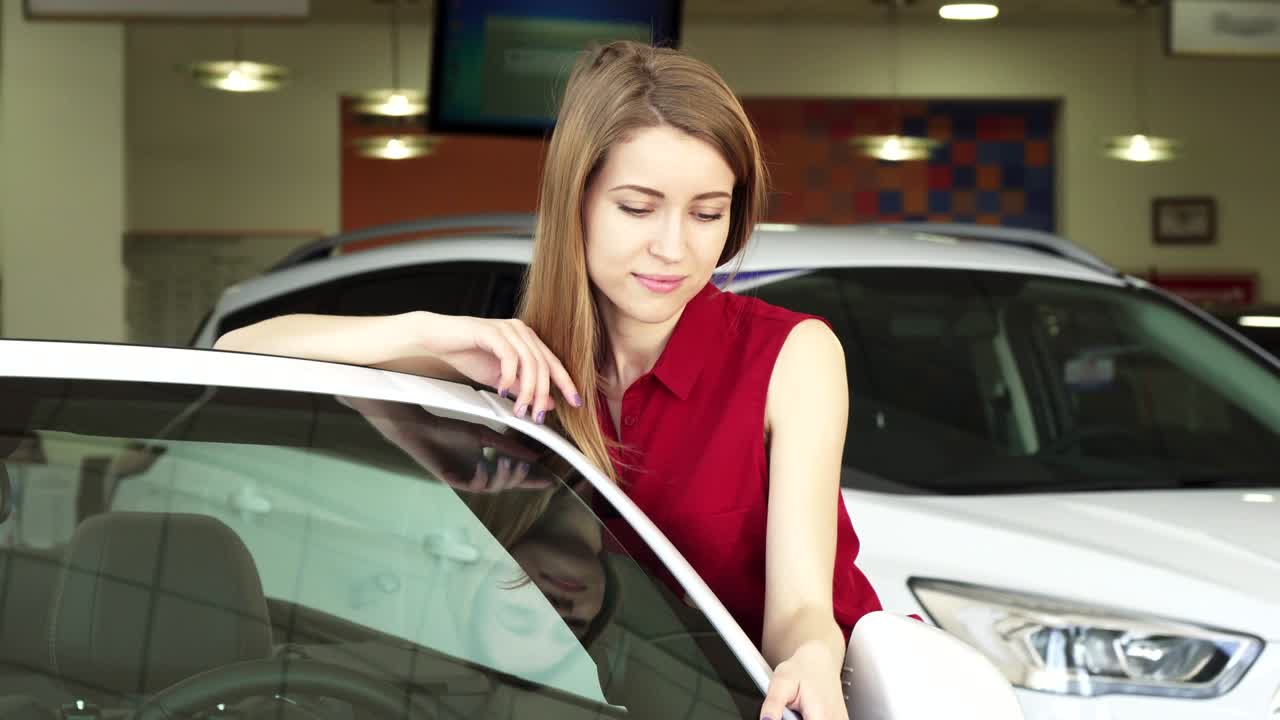 hermosa mujer joven posando con un auto nuevo en el concesionario