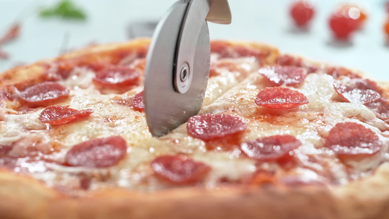 살라미와 함께 페페로니 피자는 슬로우 모션으로 피자 커터로 조각으로 잘라
