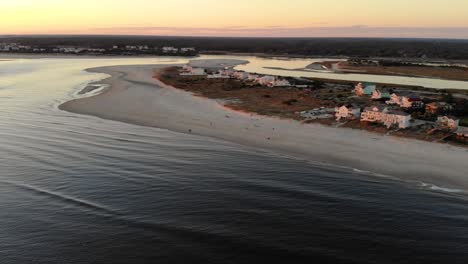 Cinematic-aerial-drone-flying-over-water-looking-onto-spectacular-oceanfront-at-beautiful-sunset