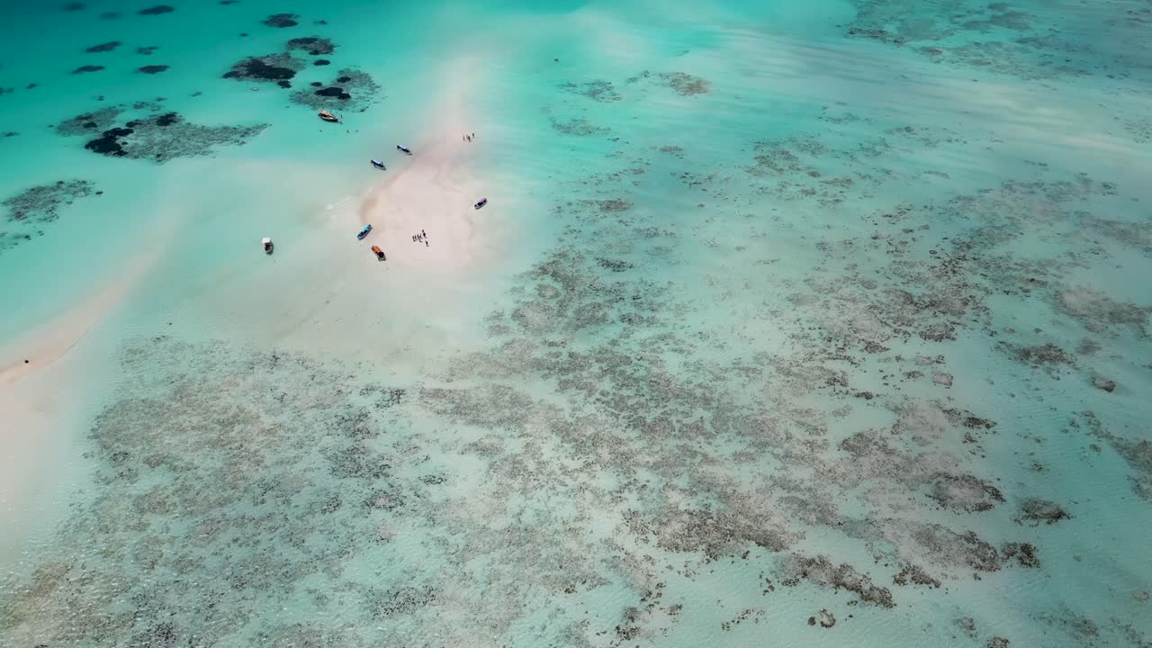 Coral reef at Mnemba island atoll in Zanzibar, Tanzania Africa with snorkeling tour boats, Aerial tilt up reveal shot