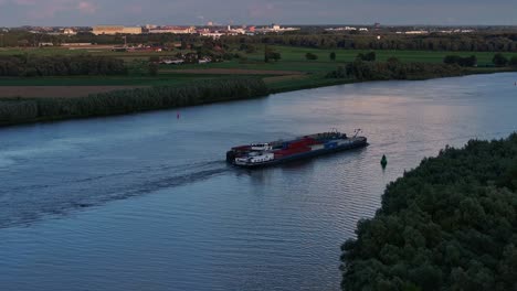 Como-Telón-De-Fondo-La-Ciudad-De-Barendrecht,-Un-Buque-Portacontenedores-Navega-Por-El-Río-Oud-Maas