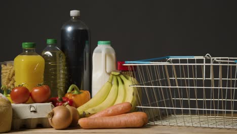 studio shot of basic food items next to supermarket wire shopping basket 4