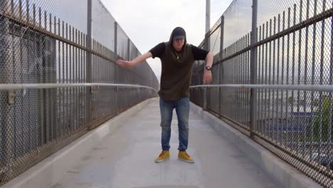 man freestyle hip hop dancing across freeway overpass in city