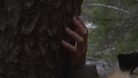 Girl-leaning-against-tree,-looking-at-a-river