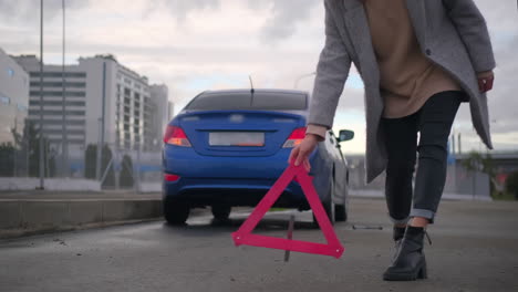 woman with warning triangle on the side of road