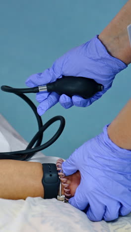 measuring the pressure for the female patient. nurse in blue latex gloves uses mechanic blood pressure gauge. close up. vertical video
