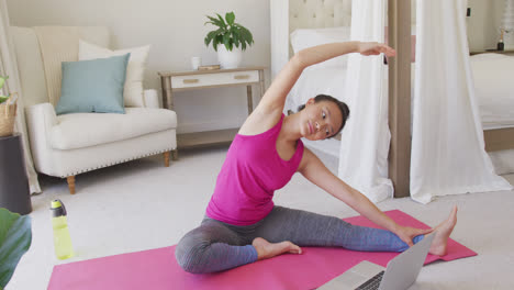 Happy-asian-woman-doing-yoga-and-stretching-in-bedroom,-in-slow-motion