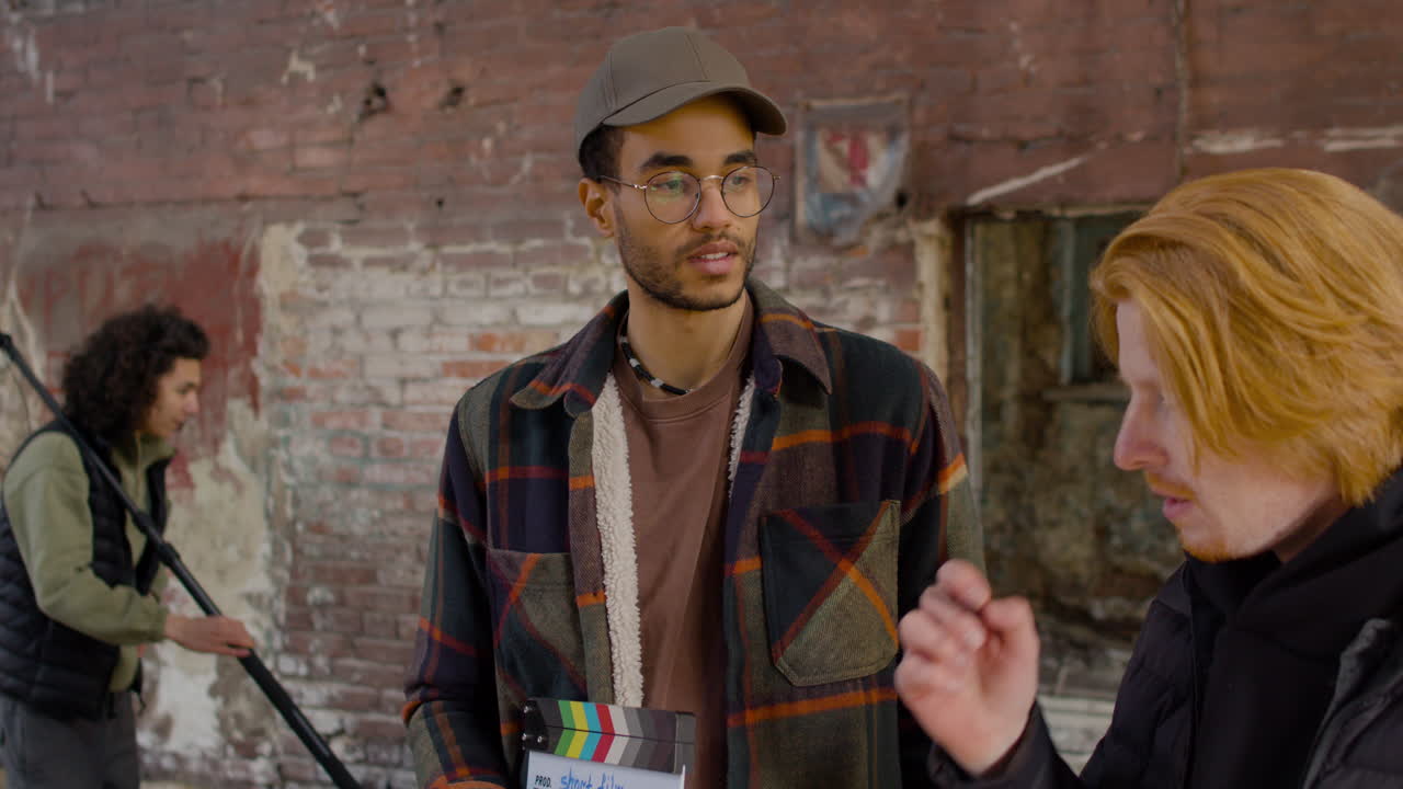 vista de cerca de dos compañeros de producción hablando y leyendo un documento sobre la película en un edificio en ruinas 2