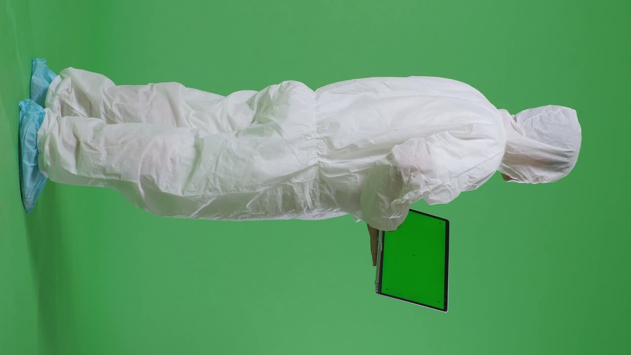 vista trasera completa del cuerpo de un científico masculino asiático usando una computadora portátil de pantalla verde mientras está de pie en el fondo de la pantalla verde