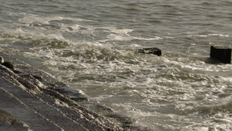 mid shot of waves crashing onto groynes and sea defences at milford on sea