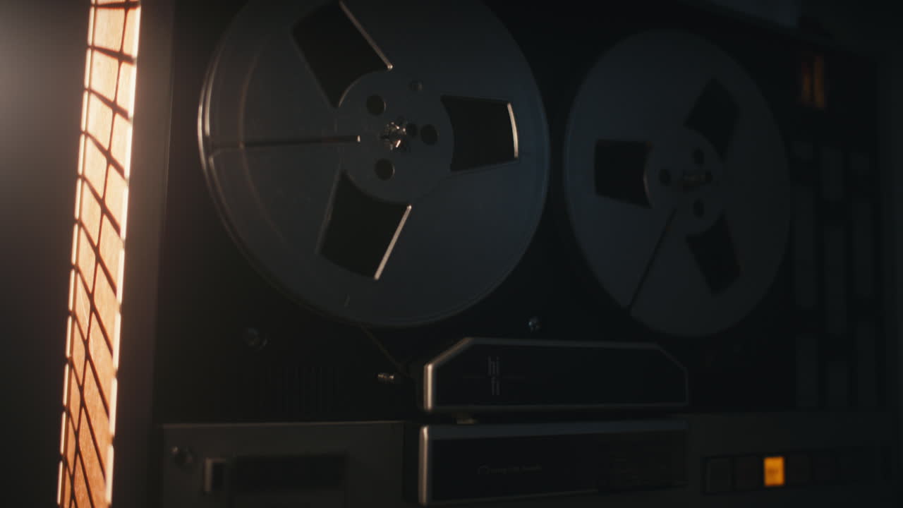 A vintage tape recorder spinning spools in a red blinking light