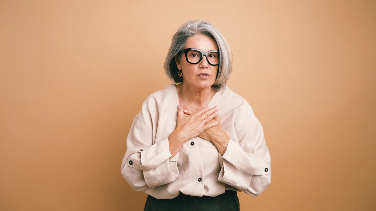 Donna matura che esprime gratitudine ed emozione con le mani giunte