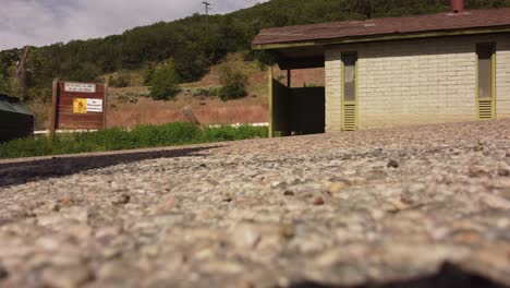 Campingplatz-Parkplatz-Badezimmer-Toiletten-Mit-Mülltonne-Oder-überspringen-Boden-Auf-Schuss-Mit-Weißem-Auto-Vorbeifahren-Dann-Clip-Umgekehrt