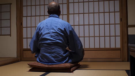 man in traditional attire sitting serenely in a japanese room, tatami flooring, with shoji doors in the background