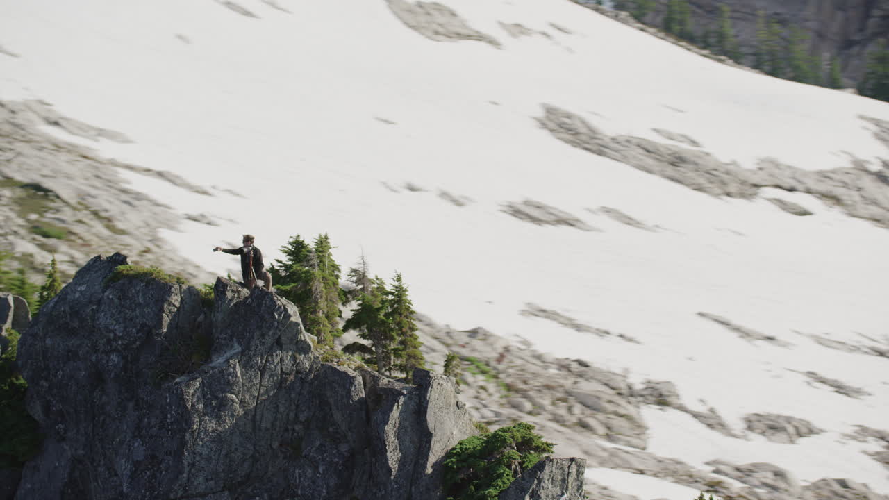 사진작가는 소나무가 있는 산 능선에 카메라로 셀카를 찍고 팀 더칸 와이드 추적 헬리콥터는 시계 반대 방향으로 느린 궤도를 돌고 있습니다.