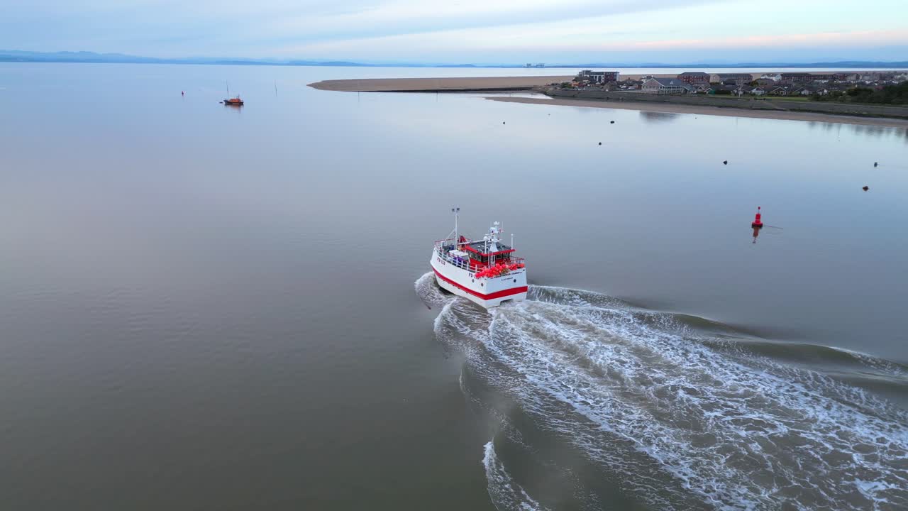 un arrastrero de pesca que se dirige al mar en aguas tranquilas al anochecer en el estuario del río wyre fleetwood lancashire reino unido con extremo de nudo