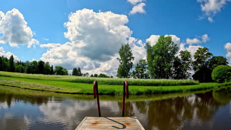 Old-footbridge-and-reflection-of-sky-in-calm-lake-water,-fusion-time-lapse