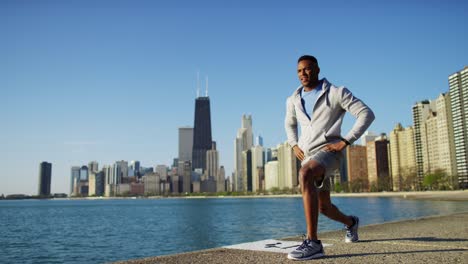 ethnic male running and stretching with smart watch