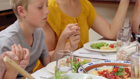 familia de varias generaciones orando antes del almuerzo