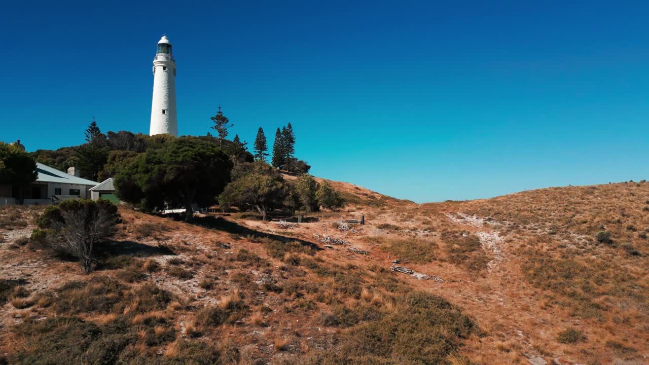 drone disparado sobre el faro de wadjemup en la isla de rottnest en un día soleado revelando la orilla del mar detrás