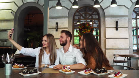 Cheerful-multiracial-friends-taking-selfie-in-pizzeria.