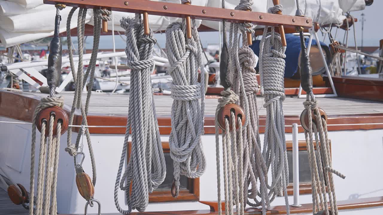 Coiled boat deck ropes neatly tied hang on rigging of sailing yacht