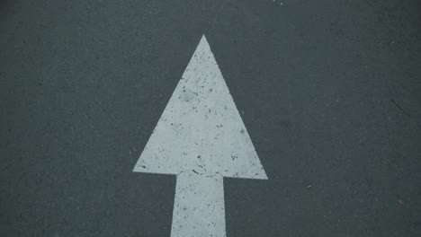 indonesian white arrow road sign on an asphalt road.