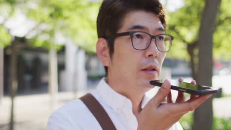 close up of asian man talking on smartphone while standing on the street