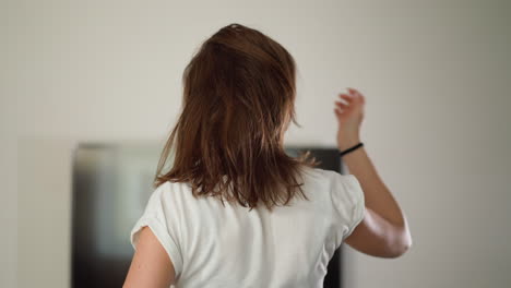 woman runs at home adjusting hair. fitness-oriented lady clad in white top engages in jogging with untethered hair in home gym. overall well-being