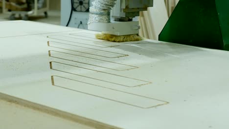 modern woodworking machine in action. cuts curly pieces from plywood sheet. production of wooden furniture