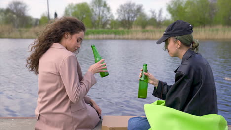 a pair of friends talking and drinking beer on the riverside