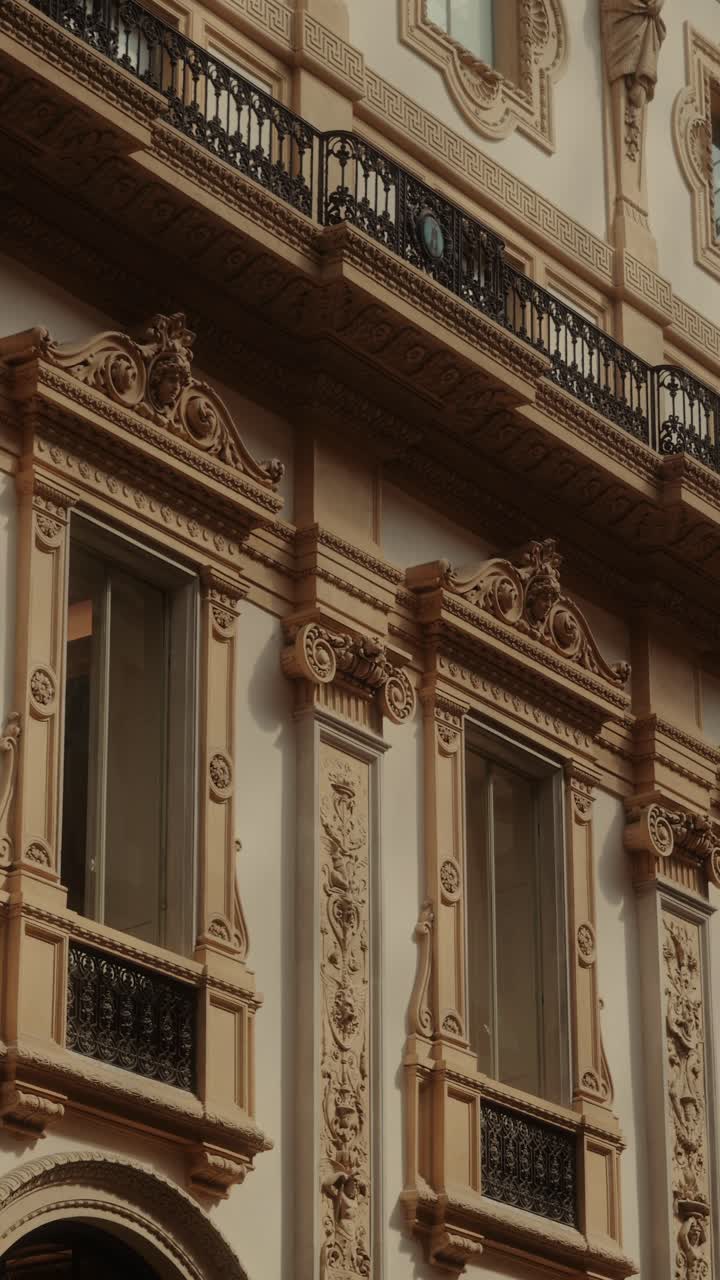 Primo piano di finestre ornate e dettagli decorativi della facciata all'interno della Galleria Vittorio Emanuele II, che evidenzia l'eleganza dell'architettura storica di Milano